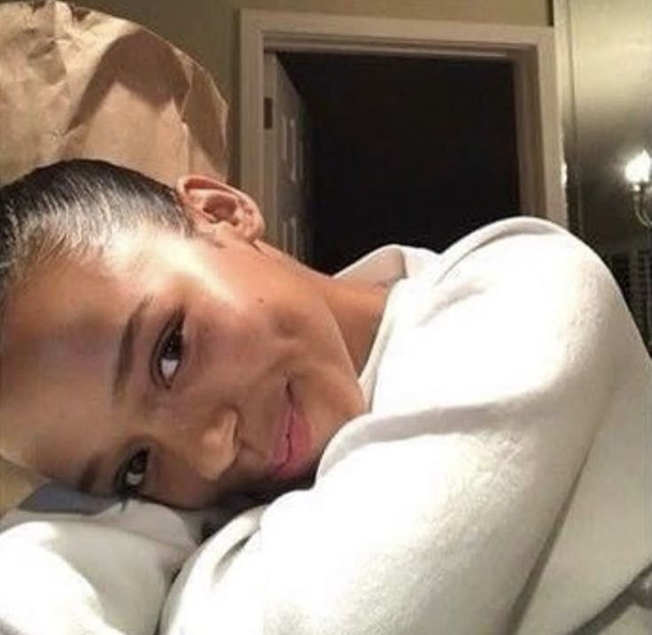 a woman laying on top of a bed under a white blanket next to a door