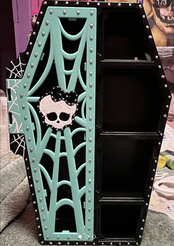 a book case with a skull on the front and side panels painted teal green