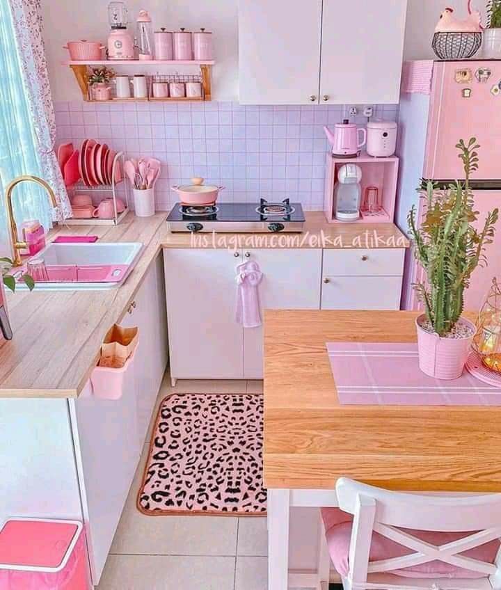 a pink and white kitchen with leopard print rugs on the floor, wooden table