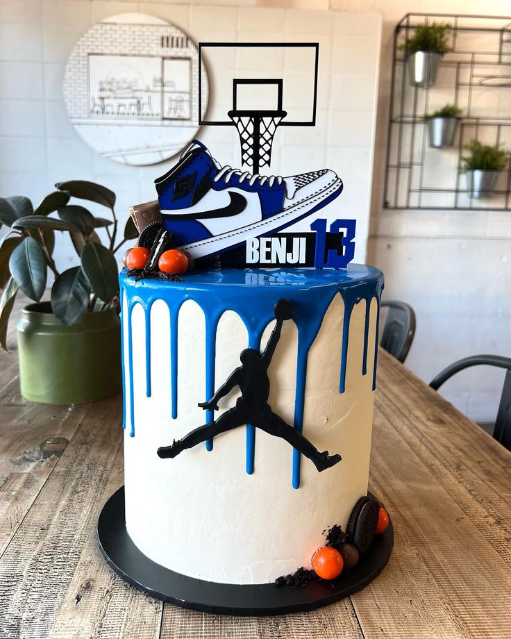 a blue and white cake with a basketball player on it's side, sitting on top of a wooden table