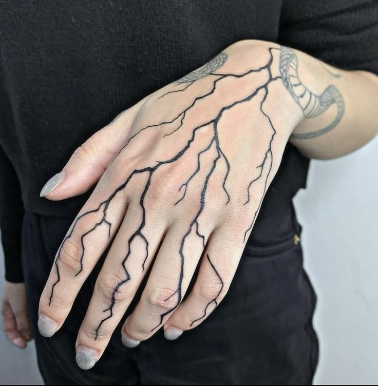 a person with tattoos on their arms and hands, holding onto a hand that has lightning drawn on it