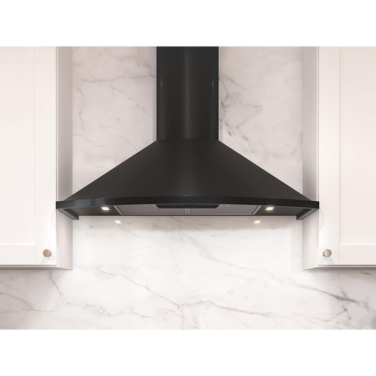 a black stove hood mounted on the side of a white kitchen cabinet with marble counter tops