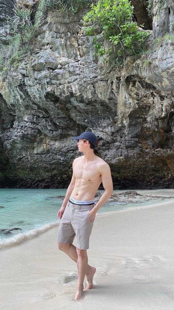 a man standing on the beach in front of a cliff