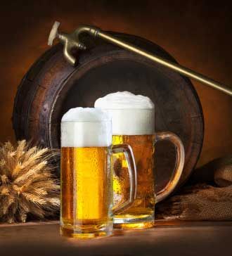 two mugs of beer sitting on top of a table next to a wooden barrel