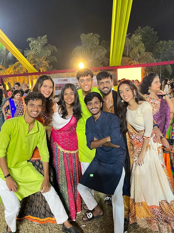 a group of people standing next to each other in front of a tent at night