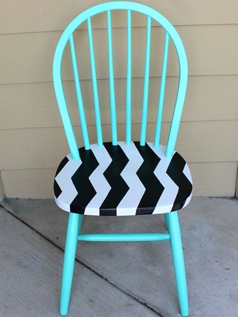 a blue chair with black and white chevrons on the back, sitting in front of a building