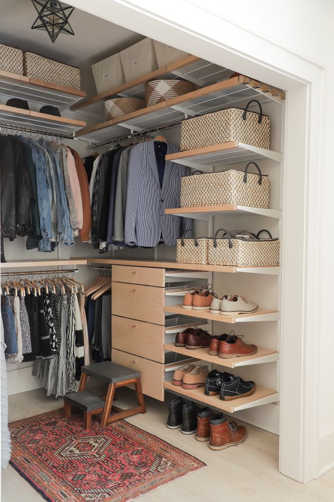 an organized closet with shoes, clothes and rugs on the floor in front of it