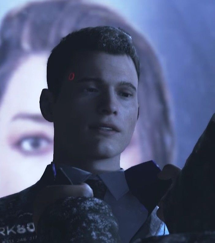 a man in a suit and tie looking at his cell phone while standing next to a large screen