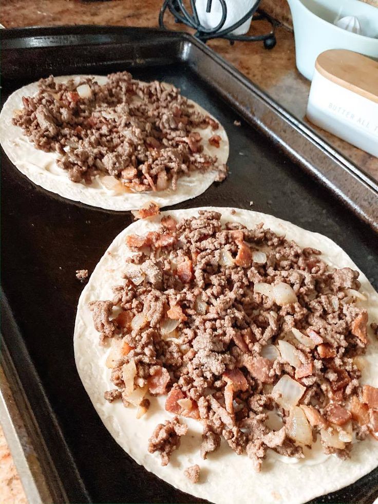 two uncooked pizzas sitting on top of a pan