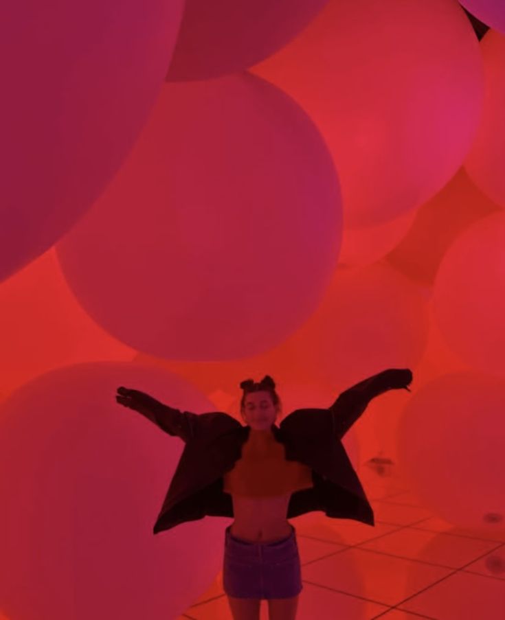 a woman standing in front of balloons with her arms outstretched