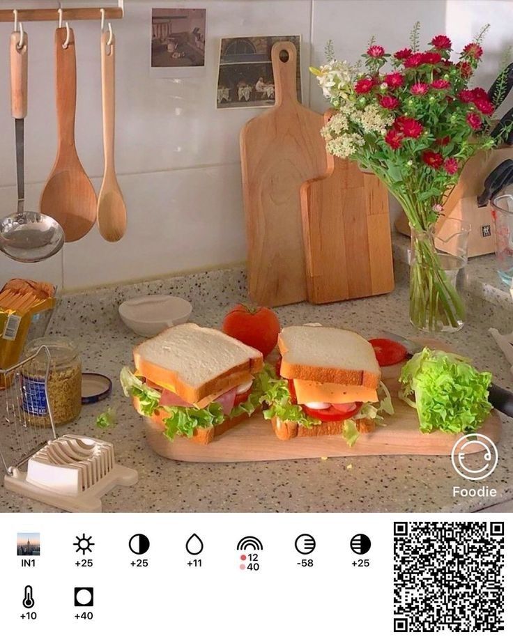 a sandwich sitting on top of a cutting board next to some utensils and flowers