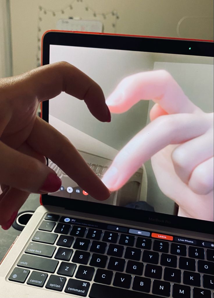 two hands touching each other on top of a laptop computer screen that is open to the web page