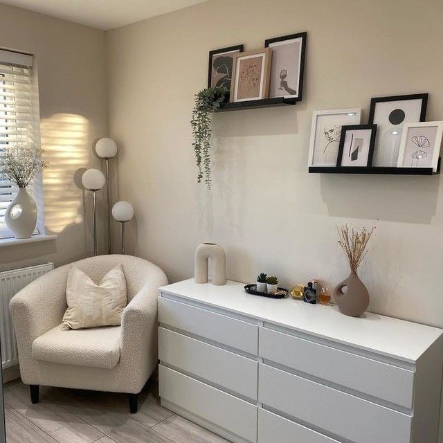 a living room with white furniture and framed pictures on the wall above it's dresser