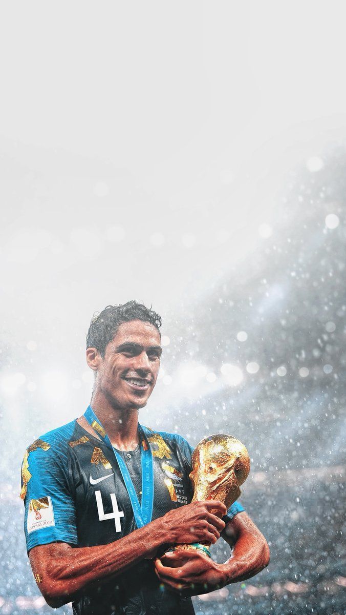 a man holding a soccer ball in his hands and smiling at the camera with rain falling on him