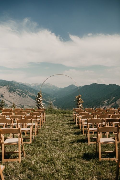 an outdoor ceremony set up with wooden chairs and mountain views in the backgroud