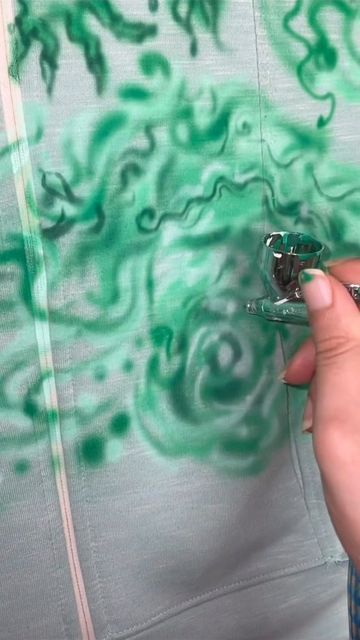 someone is painting the fabric with green paint on it and using scissors to cut off the material