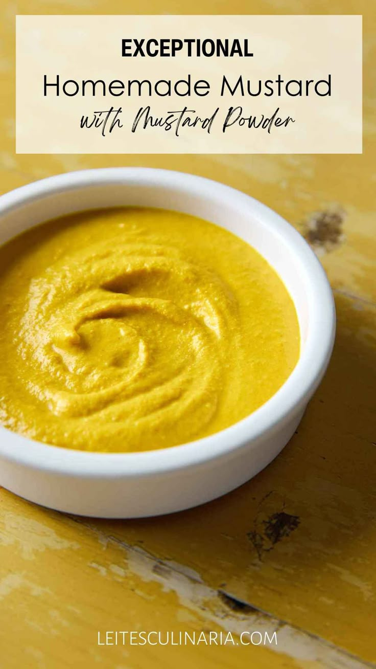 a white bowl filled with yellow hummus and the words exceptional homemade mustard over it