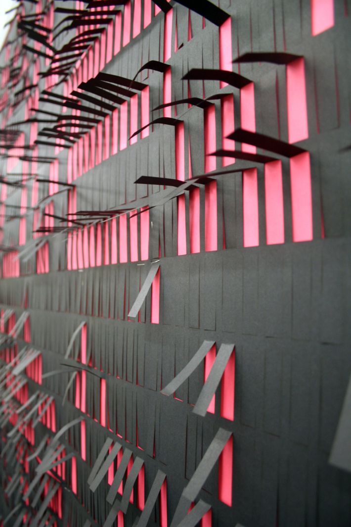 an abstract wall sculpture with red and black lines on it's sides, against a white background