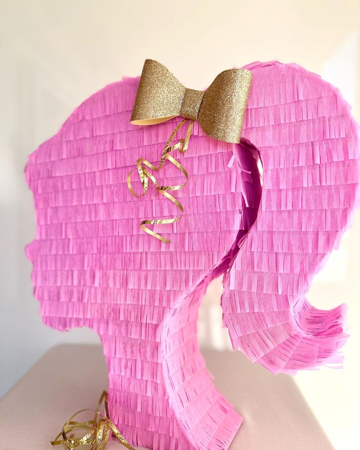 an elephant made out of pink tissue paper with a gold bow