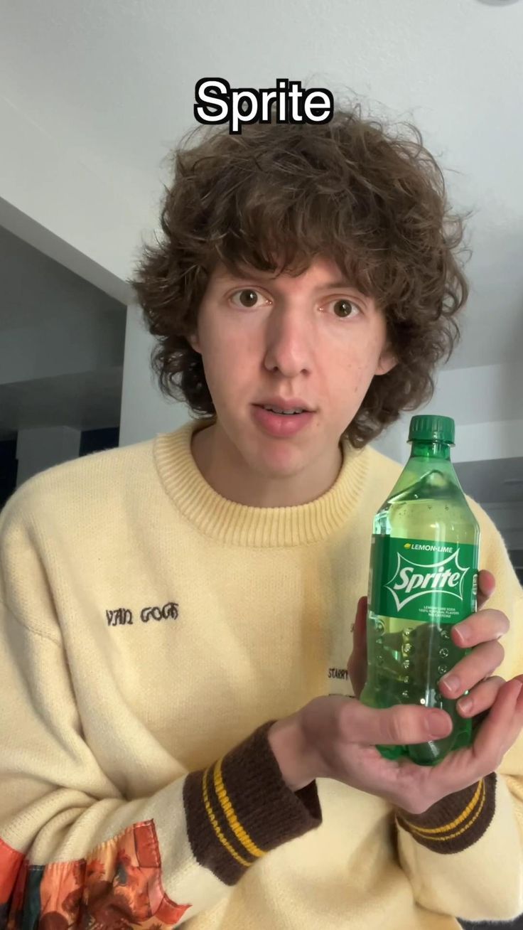 a young man holding up a bottle of water with the caption spirit on it