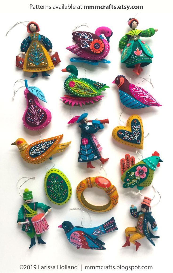 a collection of colorful bird ornaments hanging on a white wall with the words love spelled below them