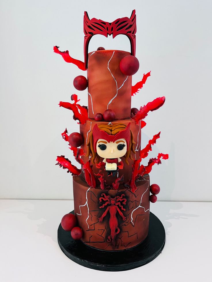 a three tiered cake with red icing and decorations on the top is decorated like a woman's face