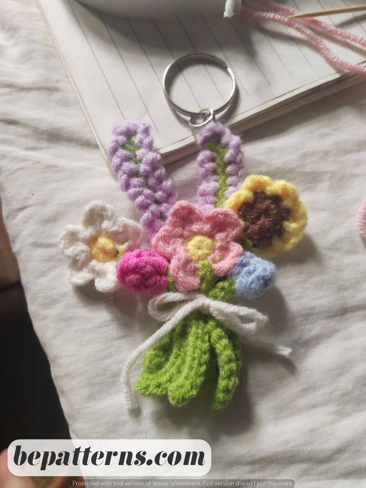 a crocheted keychain with flowers on it and a notepad in the background