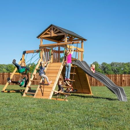 children playing on a wooden play set in the backyard with slide and climbing frame,