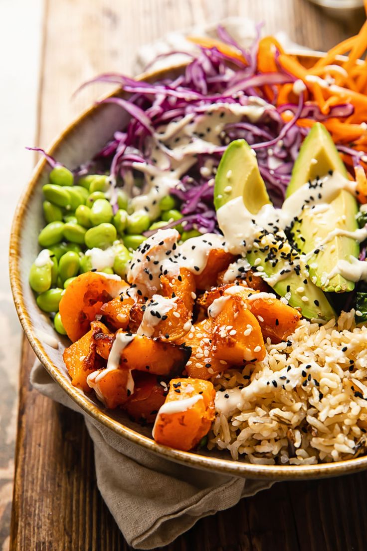 a bowl filled with rice and vegetables on top of a wooden table