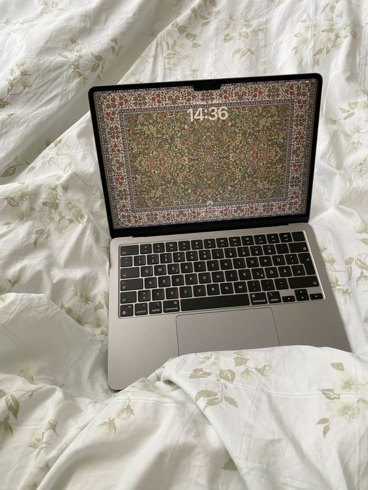 an open laptop computer sitting on top of a bed