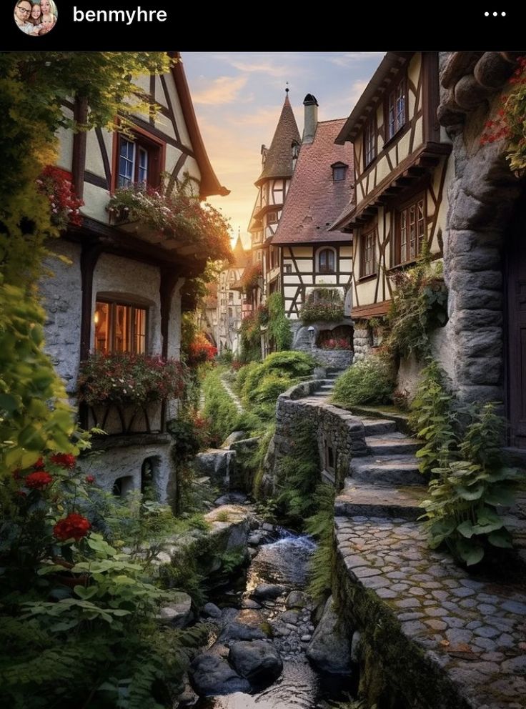 a small stream runs between two buildings in a village with flowers and greenery on either side