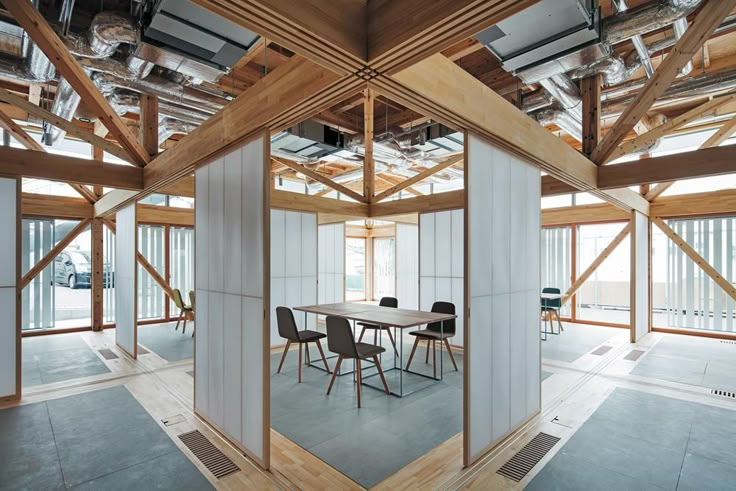 an empty room with wooden beams and chairs in the center, surrounded by white partitions