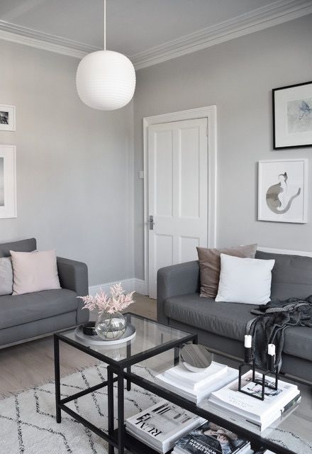 a living room with grey couches and white rugs