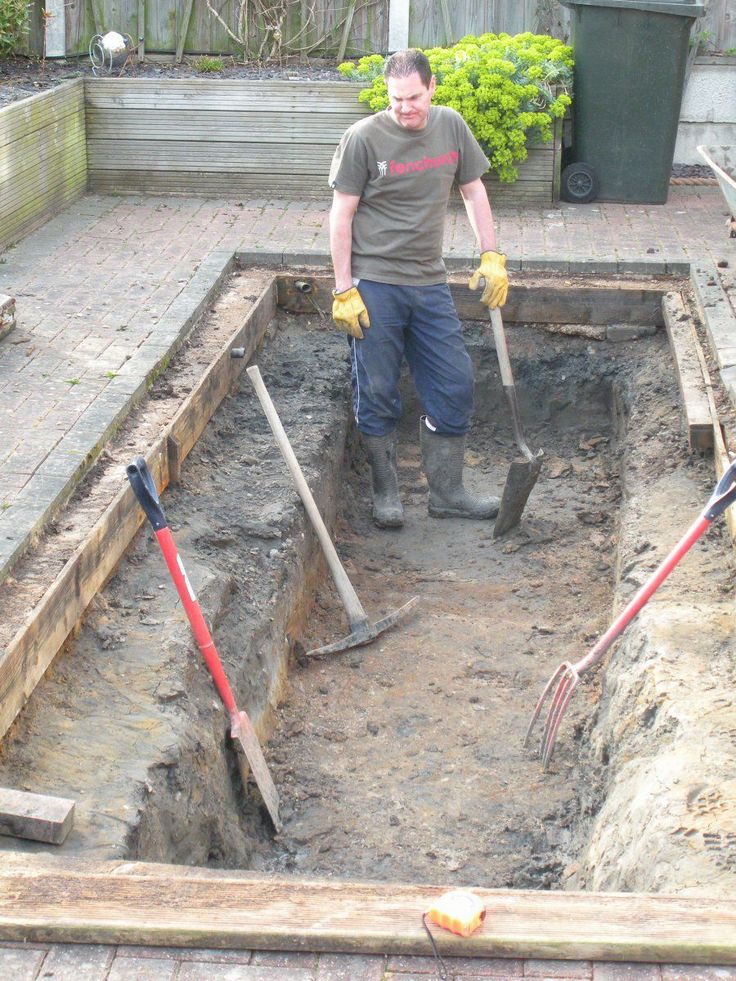 a man standing in the middle of a hole with shovels and gloves around his feet