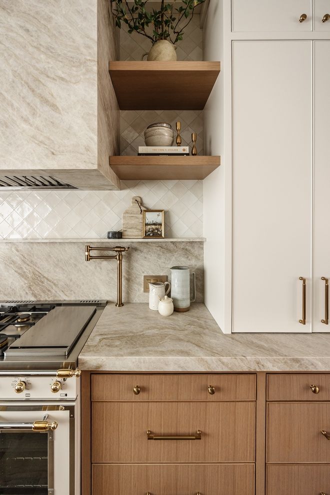 a kitchen with white cabinets and marble counter tops, gold pulls on the cabinet doors