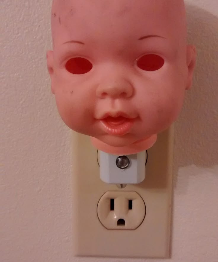 a doll head plugged in to a wall outlet