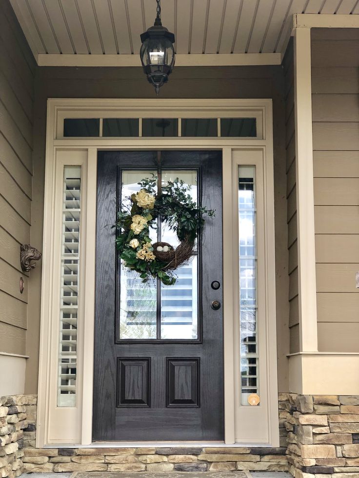 a black front door with a wreath on it and two lights hanging from the side