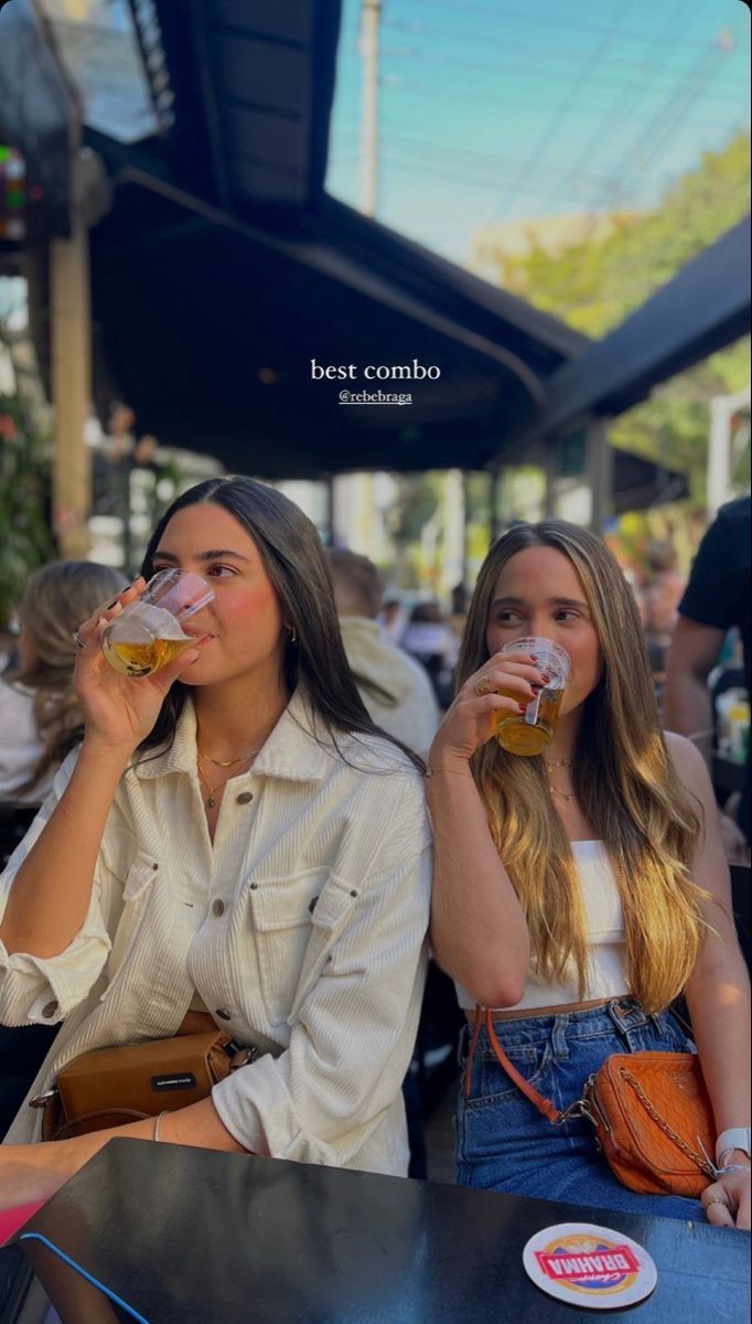 two young women sitting at a table drinking beer from cups with the caption best combo