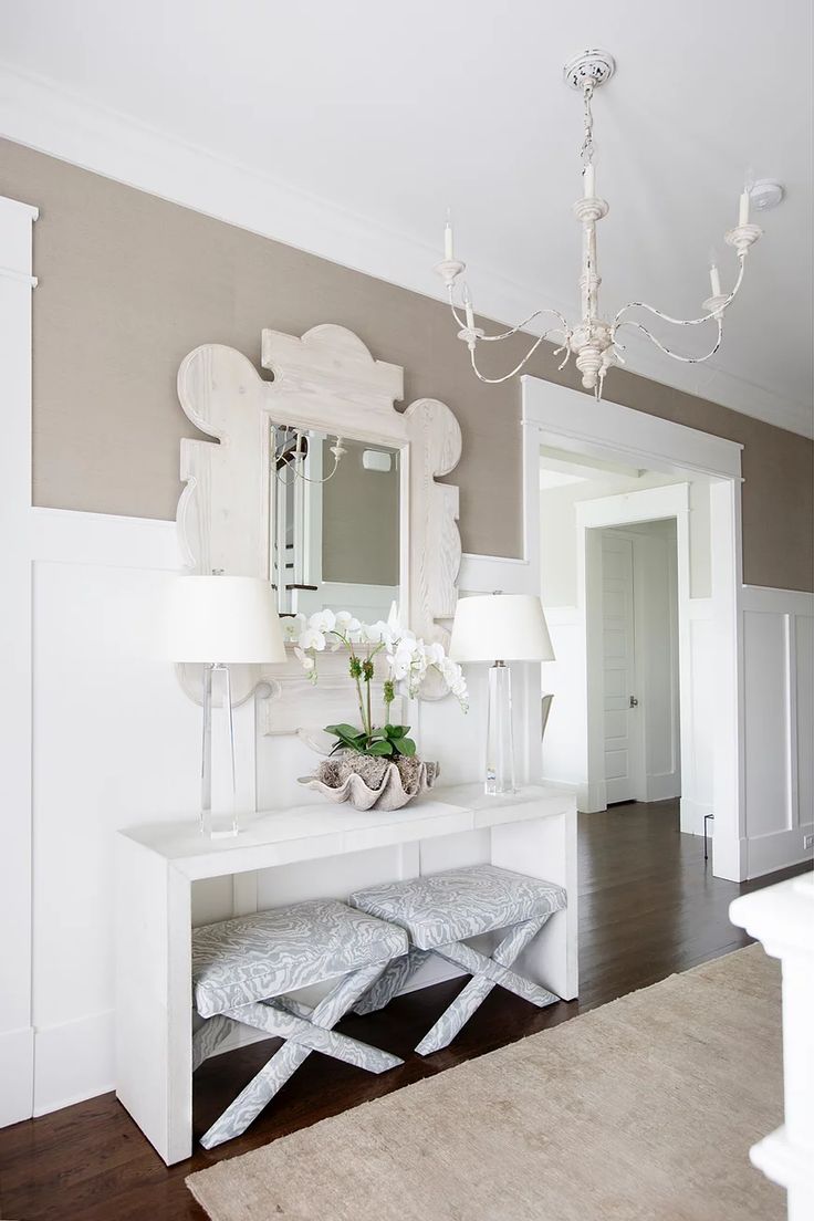 a white table with two stools and a mirror on the wall in a room