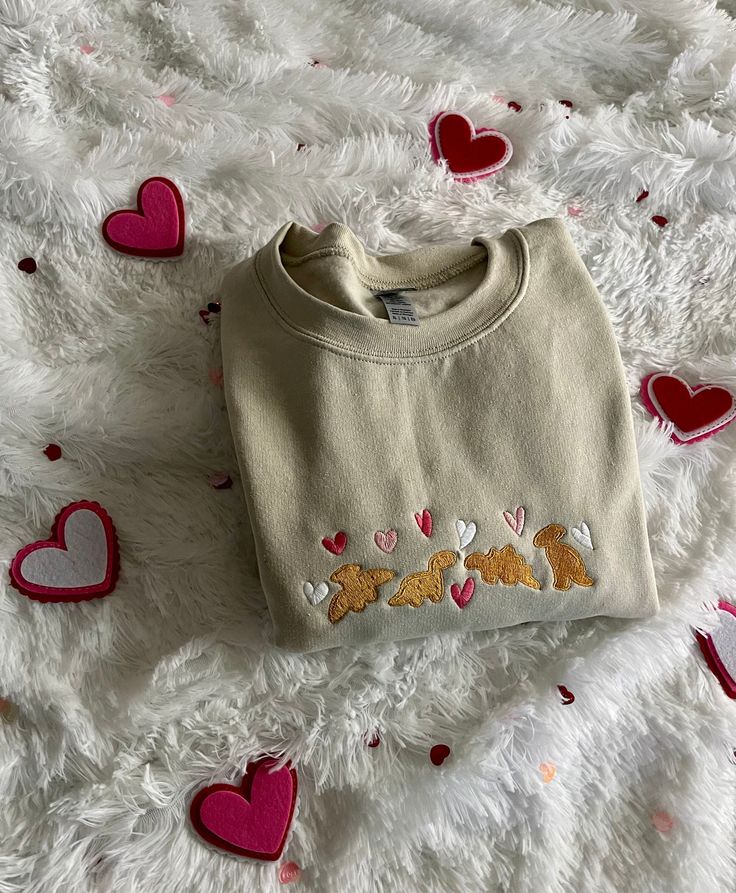 Celebrate Valentine's Day with these super cute dinosaur nuggets! Similar to our viral Christmas version, this time our dinosaur nuggets are surrounded with love and hearts! This super comfortable sweatshirt is fleece lined and will become your new favorite go to! 💕 This sweatshirt is available in 6 colors:  ✨ Hot Pink ✨ Charcoal ✨ Black ✨ Sand ✨ Navy ✨ Pink If there is a color you have in mind other than the ones available, send me a message and I can help! -Sweatshirt brand: Gildan  -Sizes av Crewneck Design Ideas, Preppy Christmas Outfit, Dino Nuggets, Manifesting Board, Valentines Galentines, Valentines Sweatshirt, Friends Cute, Gifts For Her Birthday, Christmas Gifts For Girlfriend