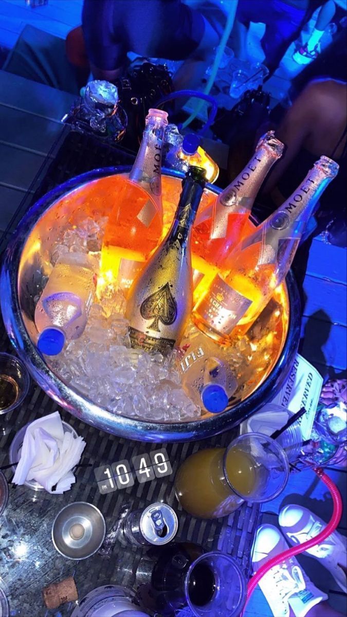 several bottles of champagne are in an ice bucket on a table with other drinks and condiments