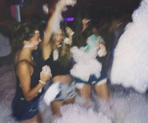 black and white photograph of people dancing in the water at a party with confetti on their heads