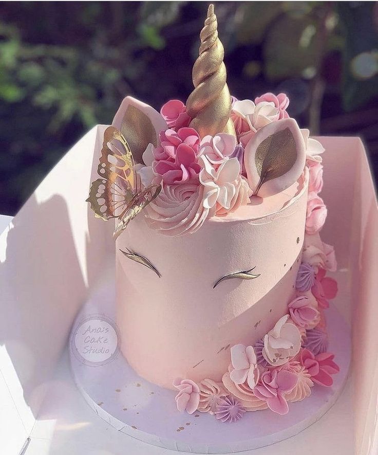 a pink cake decorated with flowers and a unicorn's head