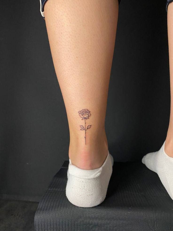 a woman's foot with a flower tattoo on her left leg and the bottom part of her legs