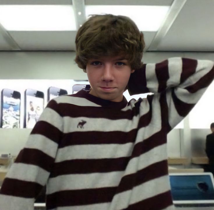 a young man with curly hair wearing a striped sweater