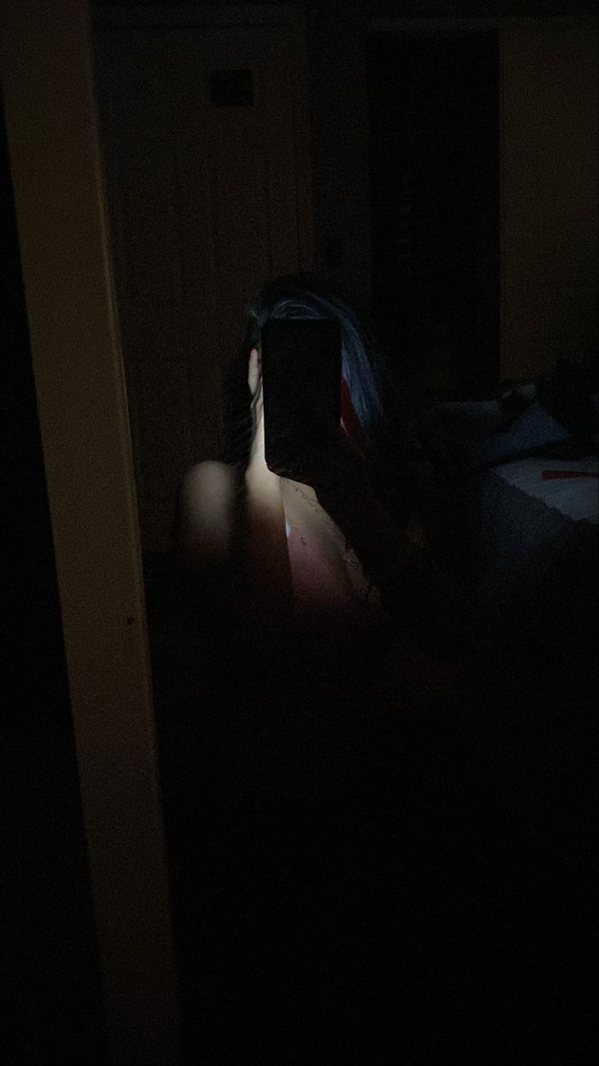 a person is taking a photo in the dark with their cell phone while sitting on a bed