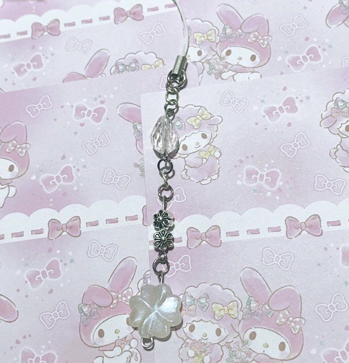 a pair of hello kitty dangling earrings on a pink and white wallpapered background