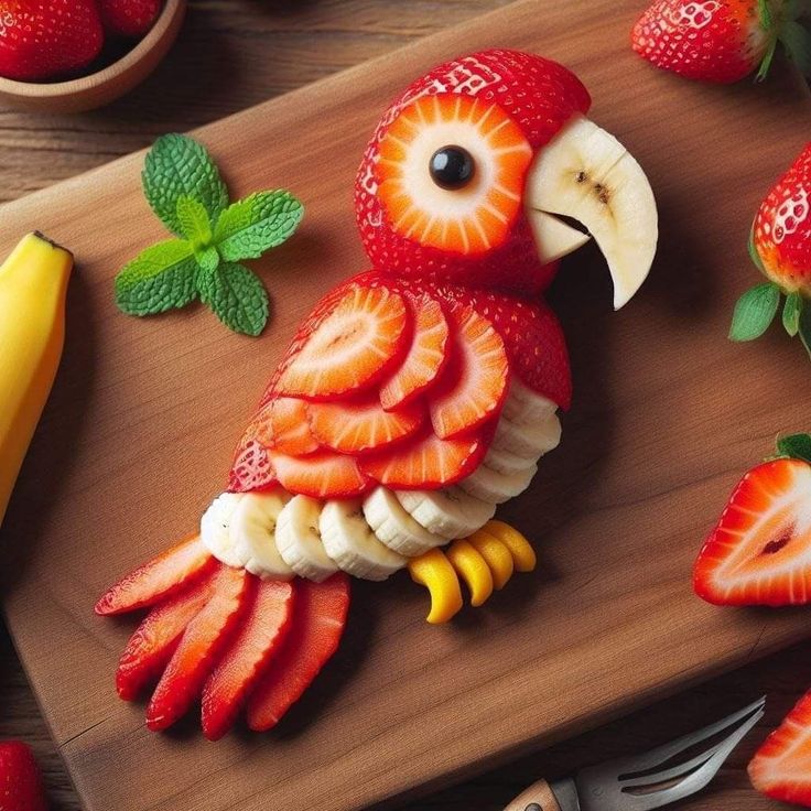 a wooden cutting board topped with sliced strawberries and an owl figurine made out of fruit