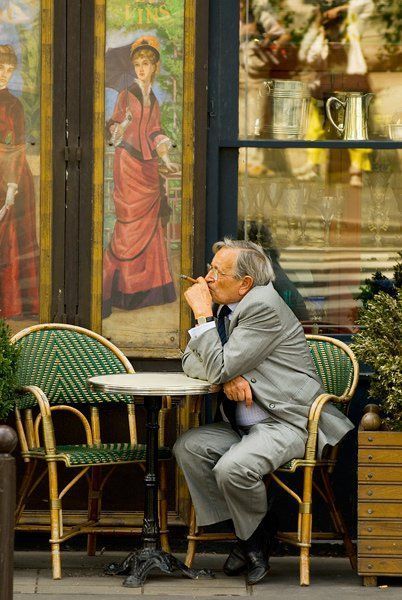 a man sitting at a table in front of a painting on the side of a building