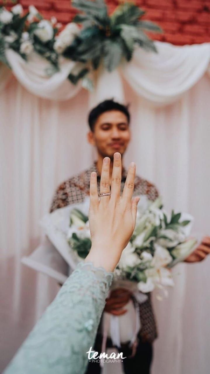 a man holding his hand up in front of a woman with her wedding ring on